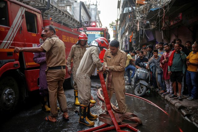 Firefighters try to join hoses so they can reach a rooftop during an ongoing fire in some textile shops at a market area in the old quarters of Delhi, India, June 13, 2024. Fire officers say electrical failures are responsible for nearly three-quarters of the blazes this summer. With Delhi sweating through what the federal weather office says is one of its longest heat waves on record, demand for air cooling has surged. (Photo by Adnan Abidi/Reuters)