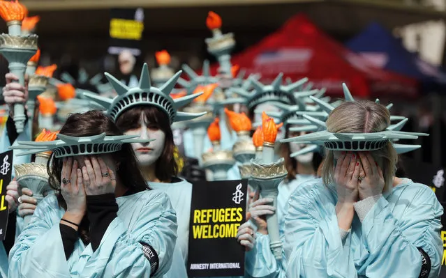 One hundred Amnesty International protesters dressed as the Statue of Liberty demonstrate outside the US Embassy in London, Thursday, April 27, 2017, marking US President Donald Trump's first 100 days in office. (Photo by Frank Augstein/AP Photo)