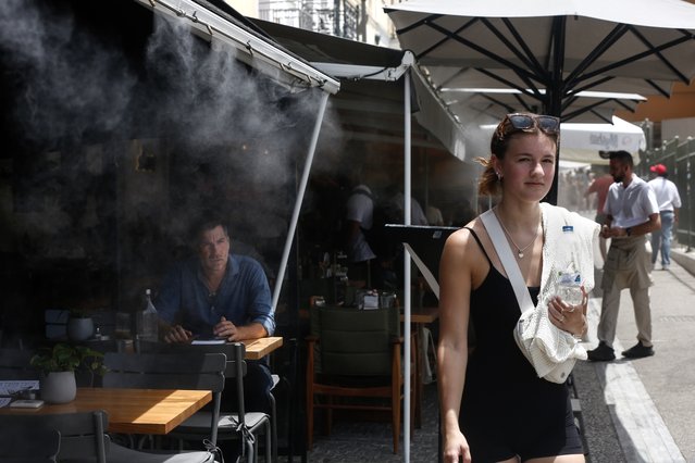 A woman walks past a terrace with a water spray device outside the Ancient Agora during a heatwave in Athens, Greece, 13 June 2024. Temperatures remain very high throughout Greece on 13 June, in many places exceeding 40 degrees Celsius. (Photo by Yannis Kolesidis/EPA/EFE/Rex Features/Shutterstock)