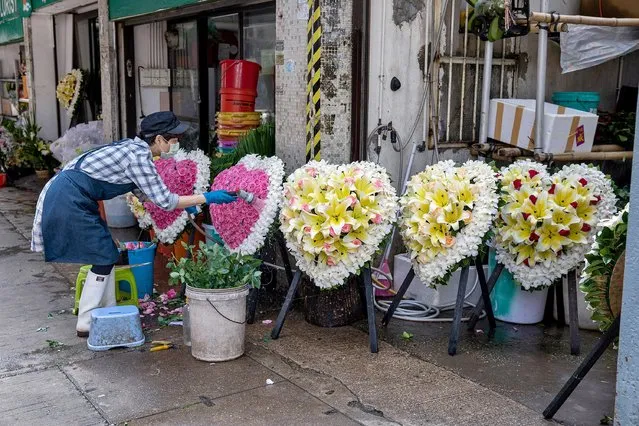 A woman water wreaths outside a funera parlor in Hong Kong, China, 18 March 2022. Over 700 coffins were due to arrive by sea from China on 18 March after local suppliers said they have had difficulties in getting them delivered due to the Covid situation both in the city and in mainland China. (Photo by Jerome Favre/EPA/EFE)