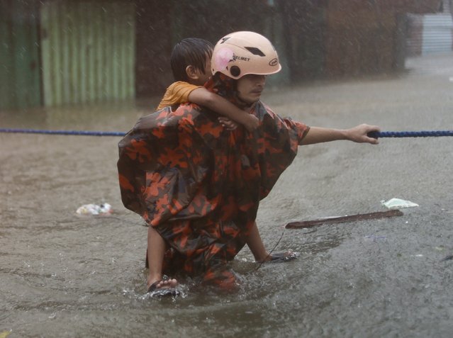 A rescuer carries a boy as they wade on rising floodwaters in Marikina city, Metro Manila, Philippines, 24 July 2024. (Photo by Francis R. Malasig/EPA/EFE)