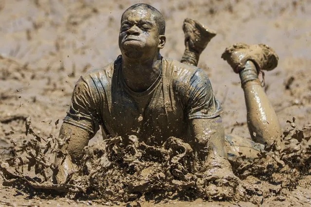 In this Sunday, June 28, 2015 photo, Geoff Green, of Columbus, Ohio, braces himself during the “Mud Mile” obstacle during a Tough Mudder event in Sparta, Ky. The obstacle course features a non-competitive format where teams assist each other through miles of running, jumping, climbing, and crawling on their way to the finish line, all for the sake of a fun challenge. (Photo by John Minchillo/AP Photo)