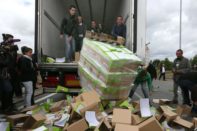 French farmers empty a truck in front of Lactalis' factory, in Laval, western France, in order to stop importation of foreign meat and milk products in France, Monday, July 27, 2015. (Photo by David Vincent/AP Photo)