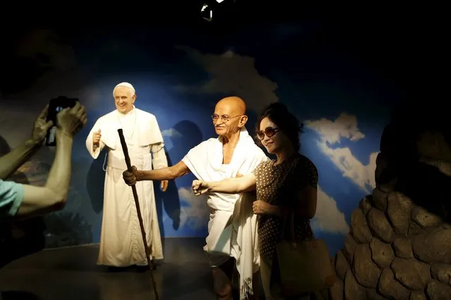A woman poses for photographs next to the wax figures of Mahatma Gandhi (C) and Pope Francis (L) at Grevin Wax Museum in central Seoul, South Korea, July 30, 2015. (Photo by Kim Hong-Ji/Reuters)