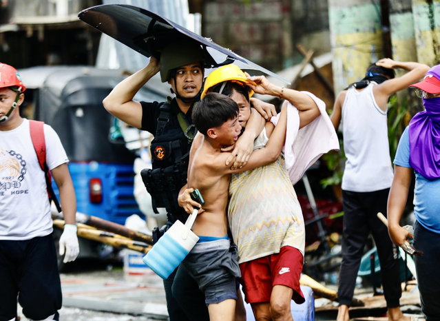 Filipino informal settlers react as they seek cover beside a police officer during a demolition raid at a shanty town in Pasay City, Metro Manila, Philippines, 01 August 2024. (Photo by Francis R. Malasig/EPA)