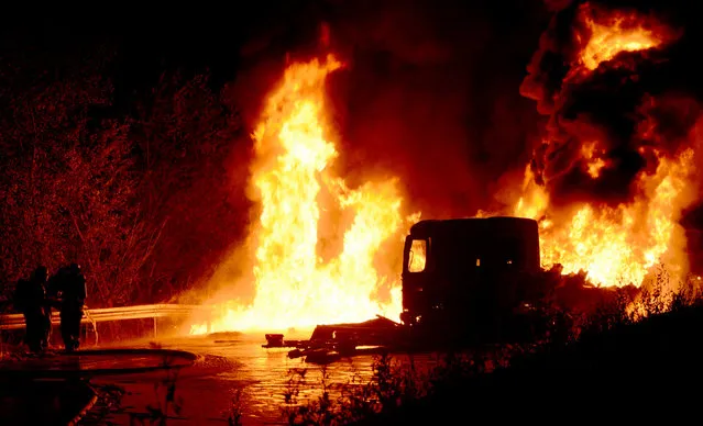 A handout picture provided by Darmstadt-Dieburg fire department shows firefighters as they try to douse a burning tanker on Autobahn 67 near Pfungstadt, Germany, July 31, 2015. The tanker, loaded with 36.000 litres of diesel and petrol, slammed into a construction vehicle according to the Darmstadt police. Three construction workers were injured but were able to escape the fire together with the tanker driver. (Photo by EPA/Darmstadt-Dieburg Fire Dept)