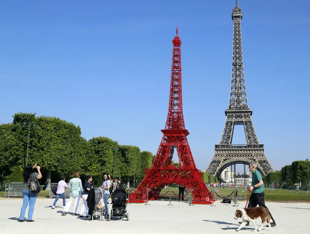 France: People stop to observe a replica of the Eiffel Tower built with red bistro chairs to mark the 125th anniversary of the Fermob company's bistro chairs in Paris June 24, 2014. Like the Eiffel Tower, the famous bistro chairs celebrate their 125th anniversary this year. (Photo by John Schults/Reuters)