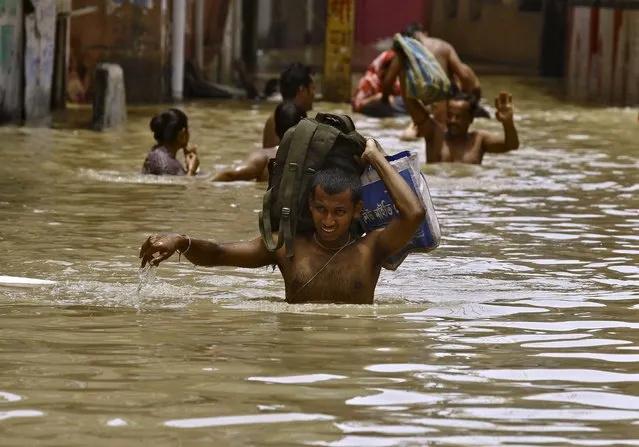 Flood-affected people carry their belongings as they move to safer grounds along a flooded street at West Midnapore district in West Bengal, India, August 4, 2015. (Photo by Rupak De Chowdhuri/Reuters)