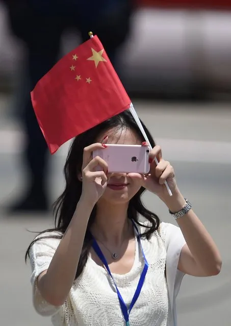 A woman holding a Chinese flag takes a photo on the tarmac ahead of the arrival of China's President Xi Jinping at Hong Kong's international airport on June 29, 2017. Xi was scheduled to arrive in Hong Kong on June 29 to mark 20 years since it was handed back to China by Britain, with leading democracy activists already in police custody after a protest in the politically divided city. (Photo by Anthony Wallace/AFP Photo)