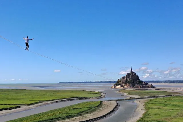 An aerial photograph shows French tightrope walker Nathan Paulin walking on a slackline in the bay of Le Mont Saint-Michel, north-western France, during his world record distance attempt, on May 24, 2022. (Photo by Damien Meyer/AFP Photo)