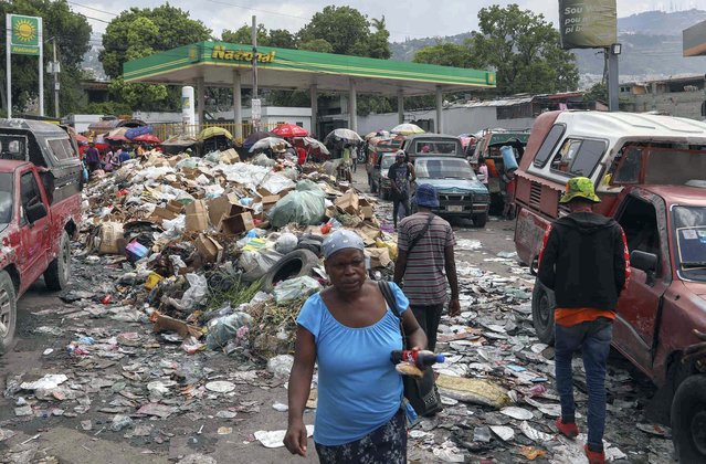 People walk past a pile of garbage in the Petion-ville neighborhood of Port-au-Prince, Haiti, Thursday, August 15, 2024. (Photo by Odelyn Joseph/AP Photo)