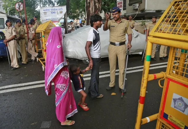 An Indian police officer stops a family at a barricade in the neighborhood of Yakub Abdul Razak Memon's family residence in Mumbai, India, Thursday, July 30, 2015. Memon, 53, the only death row convict in India's deadliest terror attack, the 1993 Mumbai bombings that killed 257 people, was hanged early Thursday after the country's president rejected a last-minute mercy plea, several newspapers and TV stations reported. (Photo by Rafiq Maqbool/AP Photo)