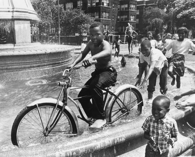 Neighborhood kids use Columbus Circle fountain on Chicago's West Side as a playground and “swimming pool”, July 7, 1967. Last summer, a riot broke out in the area over the shutting off of a fire hydrant spray for kids.  Riots were a nightly occurrence until National Guardsmen were called. (Photo by Charles Knoblock/AP Photo)