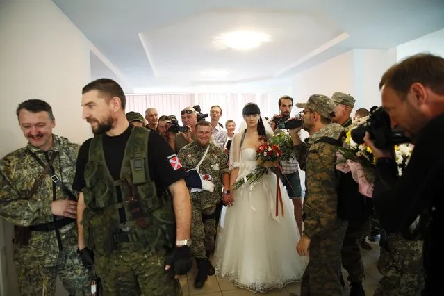 Pro-Russian separatist Arsene Pavlov, call sign “Motorola”, and his bride Elena walk surrounded by fellow separatists during a marriage ceremony in the registry office of the city of Donetsk July 11, 2014. (Photo by Maxim Zmeyev/Reuters)