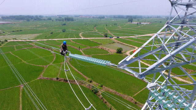 A maintenance worker checks power lines during maintenance work in Laian, in China's eastern Anhui province on July 17, 2017. China posted better-than-expected growth in the second quarter, official data showed on July 17, but authorities warned that the world's second largest economy faces external and internal risks. (Photo by AFP Photo/Stringer)