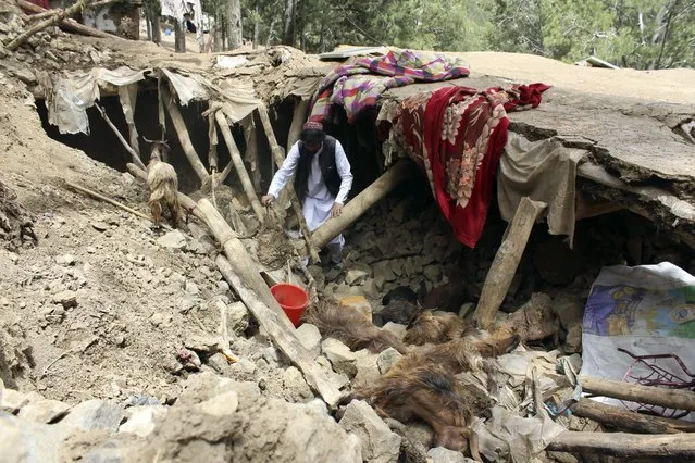 An Afghan villager collects his belongings from under the rubble of his home that was destroyed in an earthquake in the Spera District of the southwestern part of Khost Province, Afghanistan, Wednesday, June 22, 2022. A powerful earthquake struck a rugged, mountainous region of eastern Afghanistan early Wednesday, killing at least 1,000 people and injuring 1,500 more in one of the country's deadliest quakes in decades, the state-run news agency reported. (Photo by AP Photo/Stringer)