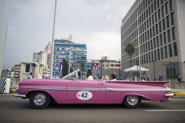 Tourists travelling in a vintage car takes pictures of the U.S embassy in Havana, Cuba August 11, 2015. (Photo by Alexandre Meneghini/Reuters)