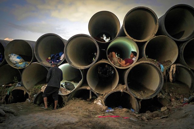 A man sits inside a concrete pipe meant for the municipal use after his shelter was swept away by the flooding Bagmati River in Kathmandu, Nepal, on Tuesday, October 1, 2024. (Photo by Niranjan Shrestha/AP Photo)