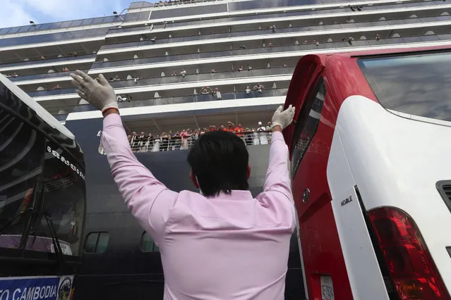 A man waves to passengers of the MS Westerdam, owned by Holland America Line, docked at the port of Sihanoukville, Cambodia, Friday, February 14, 2020. Hundreds of cruise ship passengers long stranded at sea by virus fears cheered as they finally disembarked Friday and were welcomed to Cambodia. (Photo by Heng Sinith/AP Photo)