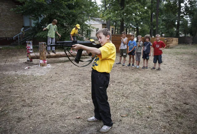 A boy with a mock weapon attends training in the youth military-patriotic summer camp “Azovets” on the outskirts of Kiev, Ukraine, 12 August 2015. The youth military-patriotic summer camp “Azovets” was organized by volunteers battalion Azov for children whose parents are in the eastern Ukrainian conflict zone and for other children from Kiev. Children learn about the military, self-defense and survival skills as well as practice sports. (Photo by Roman Pilipey/EPA)