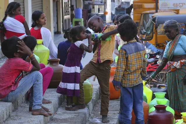An Indian boy helps a girl to drink water as others wait to collect potable water from a public tap in a poor neighborhood of Hyderabad, India, Wednesday, March 18, 2020. (Photo by Mahesh Kumar A./AP Photo)