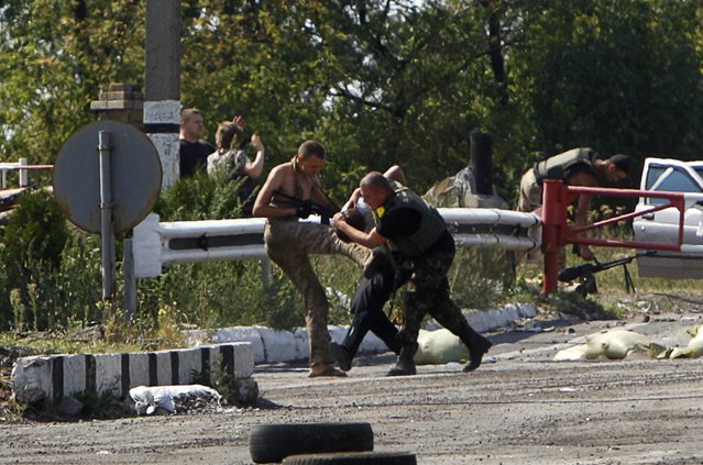 Ukrainian servicemen detain a pro-Russian activist at a checkpoint near the eastern Ukrainian town of Debaltseve, August 16, 2014. Ukrainian forces and pro-Russian separatists fought skirmishes near the Russian border on Saturday but there was no sign of the conflict widening after Kiev said it partially destroyed an armoured column that had crossed the border from Russia. (Photo by Valentyn Ogirenko/Reuters)