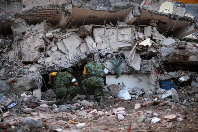 Soldiers with specially trained dogs search for survivors amid the ruins of buildings knocked down Thursday night by a 8.1- magnitude quake, in Juchitan de Zaragoza, Mexico, on September 9, 2017. Police, soldiers and emergency workers raced to rescue survivors from the ruins of Mexico' s most powerful earthquake in a century, which killed at least 61 people, as storm Katia menaced the country' s eastern coast Saturday with heavy rains. (Photo by Pedro Pardo/AFP Photo)