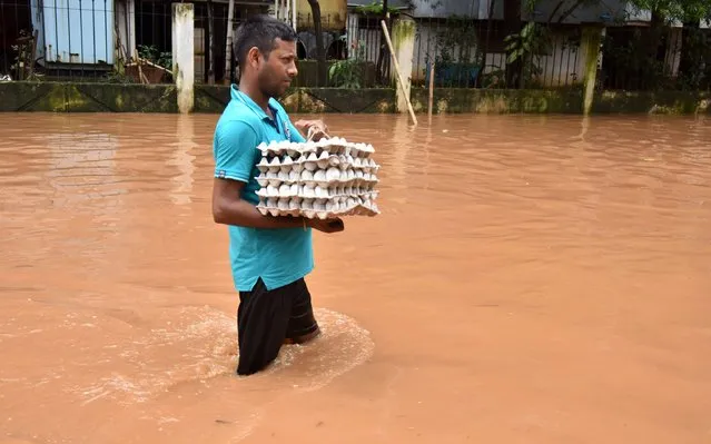 An Indian resident carries a tray of eggs as he wades through floodwaters in the Anilnagar area of Guwahati on July 19, 2016. Floods in the northern Indian state of Assam have affected people living across six districts as the annual monsoon continues to cross the Indian sub-continent. (Photo by Biju Boro/AFP Photo)