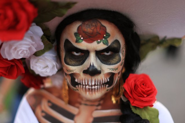 A woman walks the grounds in costume as revellers celebrate Dia De Los Muertos (Day of the Dead) at Hollywood Forever Cemetery in Los Angeles, California, on October 28, 2023. Every year on the last Saturday before November 2nd, Hollywood Forever Cemetery welcomes members of the community to celebrate Dia de Los Muertos, which reunites and honors beloved ancestors, family, and friends. (Photo by David Swanson/AFP Photo)