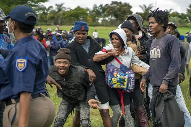 Homeless recyclers and other destitute people, some of whom said they have not eaten in three days, are asked to practice social distancing by police as they lineup in a Johannesburg park, waiting to receive food baskets from private donors, Thursday, April 9, 2020.  Because of South Africa's imposed lockdown to contain the spread of COVID-19, many people who don't have savings and are unable to work are not able to buy food. (Photo by Jerome Delay/AP Photo)