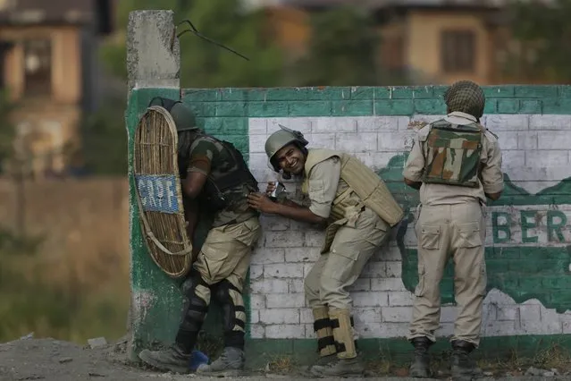 Indian paramilitary soldiers take shelter during clashes with Kashmiri stone throwers in Srinagar, Indian controlled Kashmir, Monday, July 25, 2016. The largest anti-India street protests in recent years in Kashmir erupted after Indian troops killed a popular, young rebel leader in a gunbattle on July 8. Since then, most parts of the Indian-controlled portion of Kashmir have been under security lockdown. But protests against Indian rule have persisted. (Photo by Mukhtar Khan/AP Photo)