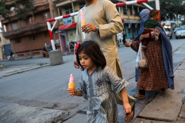 An Afghan girl with her father walk in a street in Kabul, Afghanistan on June 5, 2022. (Photo by Ali Khara/Reuters)