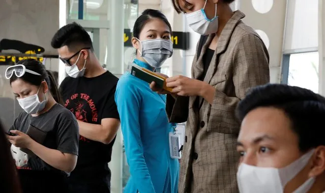 A ground staff member of Vietnam Airlines and passengers wearing protective mask, following an outbreak of the novel coronavirus, wait for boarding at the Danang airport in Danang city, Vietnam, February 23, 2020. (Photo by Reuters/Kham)