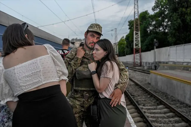 A Ukrainian soldier hugs his partner prior to board a train to Dnipro at the train station of Odessa on July 24, 2022 amid the Russian invasion of Ukraine. (Photo by Bulent Kilic/AFP Photo)