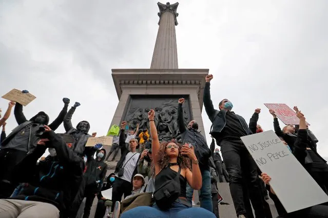 Activists, some wearing face coverings or face masks as a precautionary measure against COVID-19, hold placards as they attend a Black Lives Matter protest at Nelson's Column in Trafalgar Square in London on June 12, 2020. Britain has seen days of protests sparked by the death in police custody of George Floyd, an unarmed black man, in the United States. (Photo by Tolga Akmen/AFP Photo)