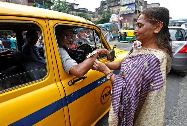 A woman ties “Rakhi” or traditional Indian sacred thread onto the wrists of a taxi driver during Raksha Bandhan celebrations in Kolkata, India, August 18, 2016. (Photo by Rupak De Chowdhuri/Reuters)