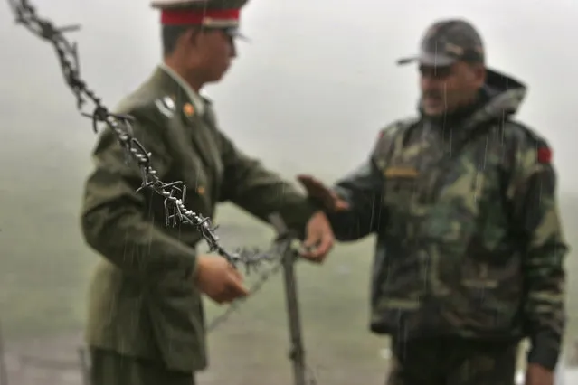 In this July 5, 2006 file photo, a Chinese soldier, left, and an Indian soldier put into place a barbed wire fence removed temporarily for Chinese officials to cross back to their country after a meeting with their Indian counterparts at the international border at Nathula Pass, in northeastern Indian state of Sikkim. Chinese and Indian military commanders have agreed to disengage their forces in a disputed area of the Himalayas following a clash that left at least 20 soldiers dead, both countries said Tuesday, June 23, 2020. (Photo by Gurinder Osan/AP Photo/File)