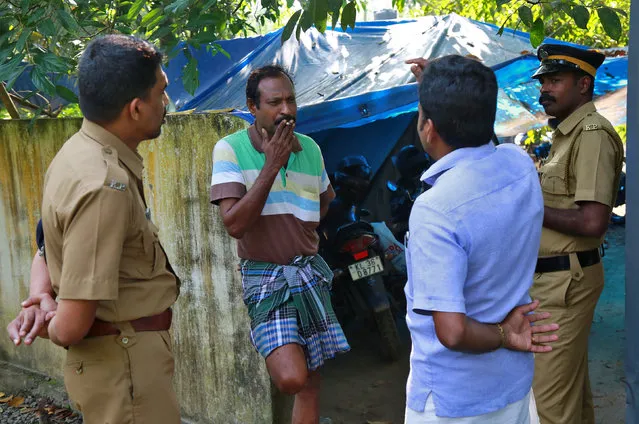 K M Ashokan (2-L), father of 24-year-old Akhila, who converted to Islam in 2016 and took a new name, Hadiya, smokes while speaking with a friend, as police officers stand guard outside his house at Vaikom in the Kottayam district of the southern state of Kerala, India November 23, 2017. (Photo by Sivaram V/Reuters)