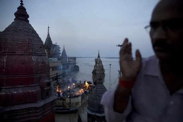 In this Thursday, August 25, 2016 photo, Hindu funerals are performed atop of a Hindu temple at the flooded Manikarnika Ghat in Varanasi, India. (Photo by Tsering Topgyal/AP Photo)