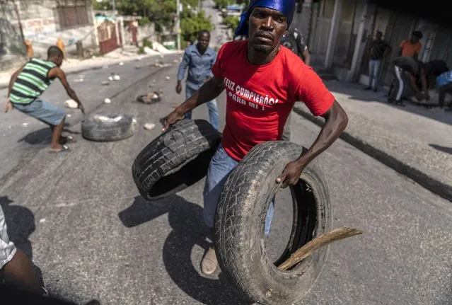 People gather tires to set up a barricade in protest over the death of journalist Romelo Vilsaint, in Port-au-Prince, Haiti, Sunday, October 30, 2022. Vilsaint died Sunday after being shot in the head when police opened fire on reporters demanding the release of one of their colleagues who was detained while covering a protest, witnesses told The Associated Press. (Photo by Ramon Espinosa/AP Photo)