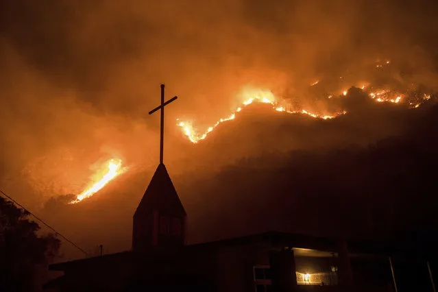 Flames from a wildfire advance down a hillside near the Springs of Life Church in Casitas Springs, Calif., on Tuesday, December 5, 2017.  Wind-driven fires tore through California communities Tuesday for the second time in two months, leaving hundreds of homes feared lost and uprooting tens of thousands of people. (Photo by Noah Berger/AP Photo)