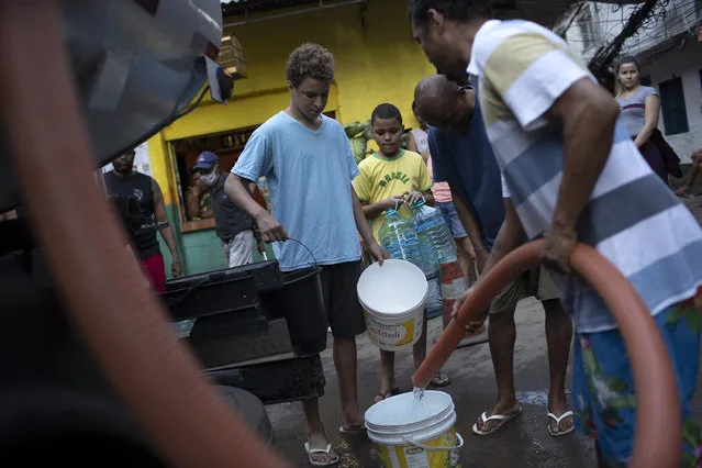 Residents fill their buckets with water provided by the local water utility from a tanker truck, amid the new coronavirus pandemic at the Rocinha slum, in Rio de Janeiro, Brazil, Thursday, July 23, 2020. In the middle of the pandemic where cleaning is essential to combat the virus, hundreds of residents from the Rocinha slum, have been suffering for more than 10 days without water. (Photo by Silvia Izquierdo/AP Photo)