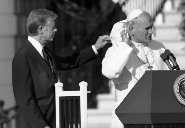 U.S. President Jimmy Carter gives Pope John Paul II a hand with his cape, blown up by a breeze during ceremonies on the South Lawn of the White House in Washington, Saturday, October 6, 1979. (Photo by AP Photo)