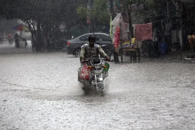 A man drives his motorbike through a flooded road during heavy rain in Lahore, Pakistan September 22, 2015. (Photo by Mohsin Raza/Reuters)