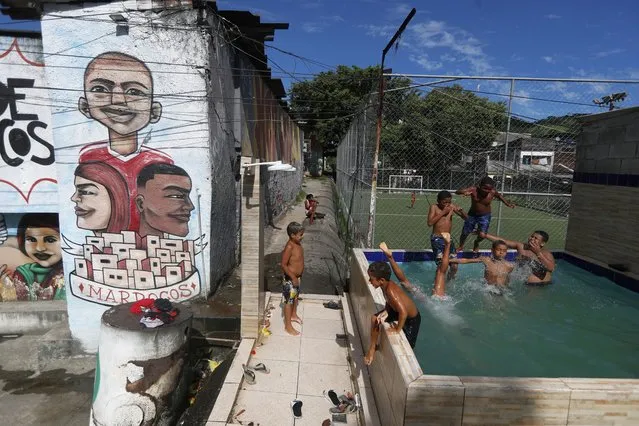 Children swim in a community pool before the start of the semifinal soccer match between the Morocco and France at the World Cup, hosted by Qatar, on a street named Morocco in the Vila Kennedy favela of Rio de Janeiro, Brazil, Wednesday, December 14, 2022. (Photo by Bruna Prado/AP Photo)