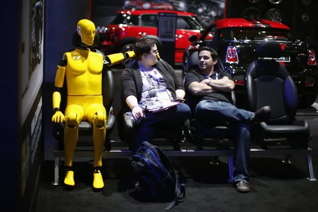 Members of the media take a break next to a crash test dummy at the 2014 Los Angeles Auto Show in Los Angeles, California November 20, 2014. (Photo by Lucy Nicholson/Reuters)