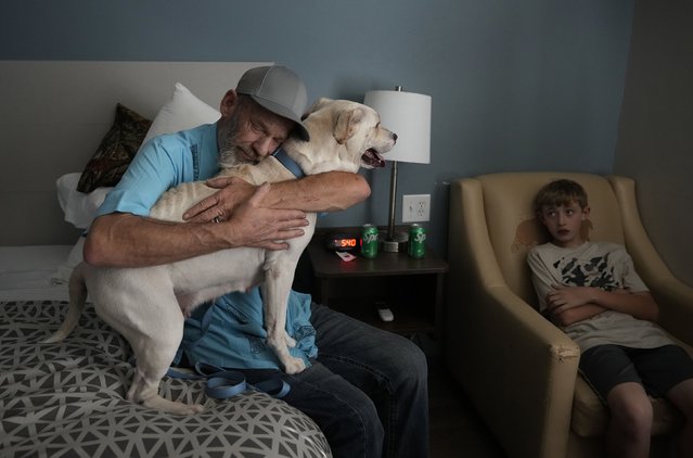 James Bell hugs one of his dogs at a hotel in Georgetown, Texas, on Thursday, July 10 2025. Bell, his wife, their three children and their two dogs were staying at the hotel after they lost their home and all of their belongings in the catastrophic flooding that devastated parts of central Texas. (Photo by Jay Janner/Austin American-Statesman)