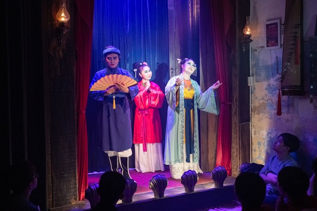 A cai luong act is performed as part of the “Kieu Nguyet Nga” show, Vietnam's traditional opera, inside the living-room theater of an aging apartment block on July 26, 2025, in Ho Chi Minh City, Vietnam. In 2018, Leon Quang Le directed Song Lang, a film that captured the golden age of “cai luong” and celebrated the art form's centennial. Today, he brings that spirit back to life with Ganh Hat Thien Ly, the fictional troupe from his film, reimagined in real life. Every week, Leon transforms his 40m2 apartment into a stage: folding chairs, a handful of guests, and actors performing just inches away. The shows, offered free of charge, draw 30 to 50 people each time, many of them seeing this traditional art form for the very first time. (Photo by Thanh Hue/Getty Images)