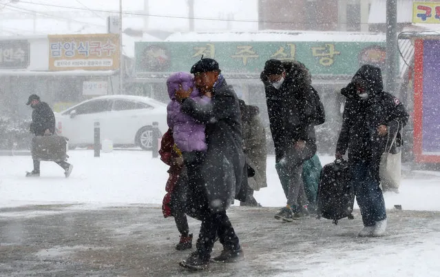 Passengers make their way through a heavy snow to a railway station in Gwangju, South Korea on January 24, 2023. (Photo by  Yonhap via Reuters)