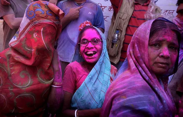 An elderly Indian Hindu woman and other devotees react as they are covered with colored powder. (Photo by Manish Swarup/Associated Press)